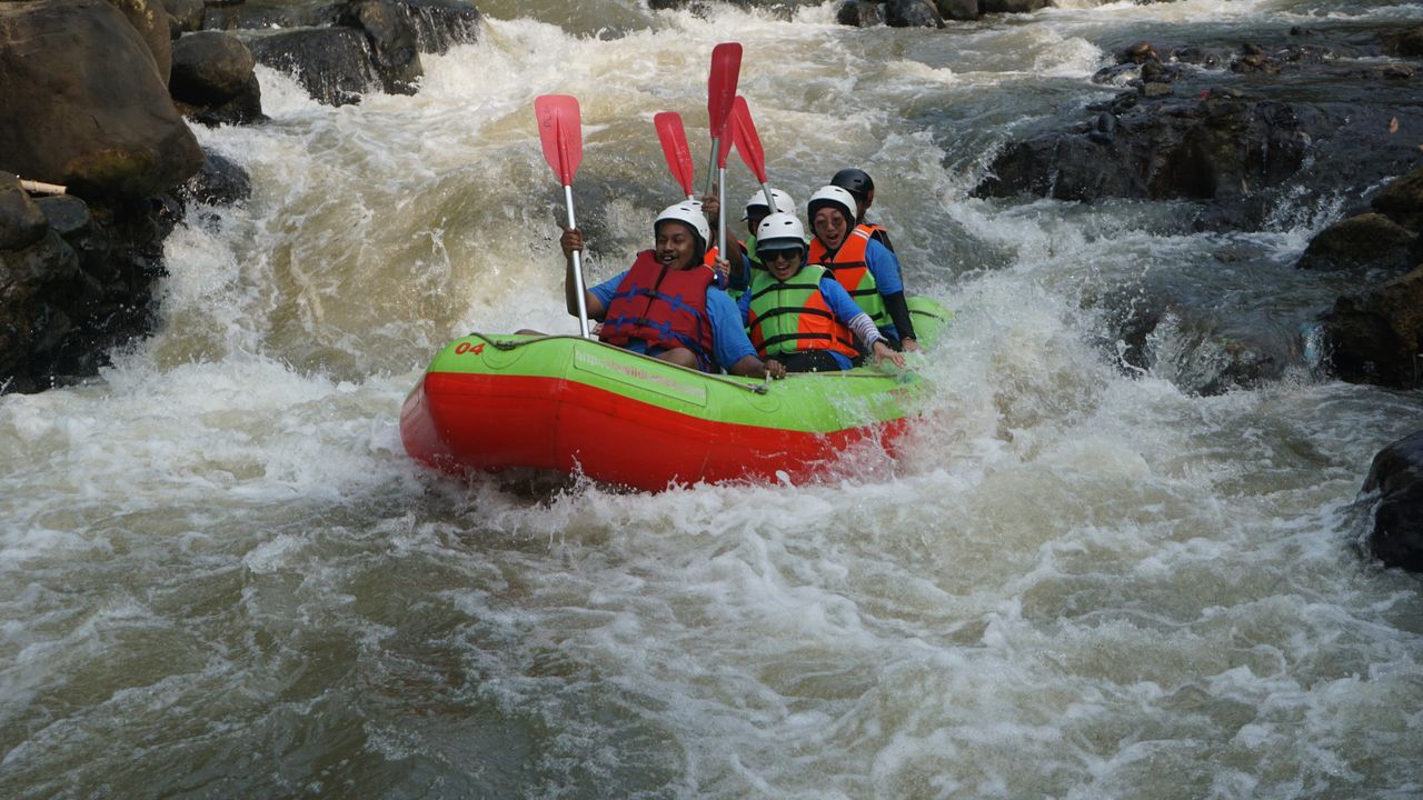 Tim peserta rafting mengangkat dayung di jeram Sungai Cisadane, Bogor